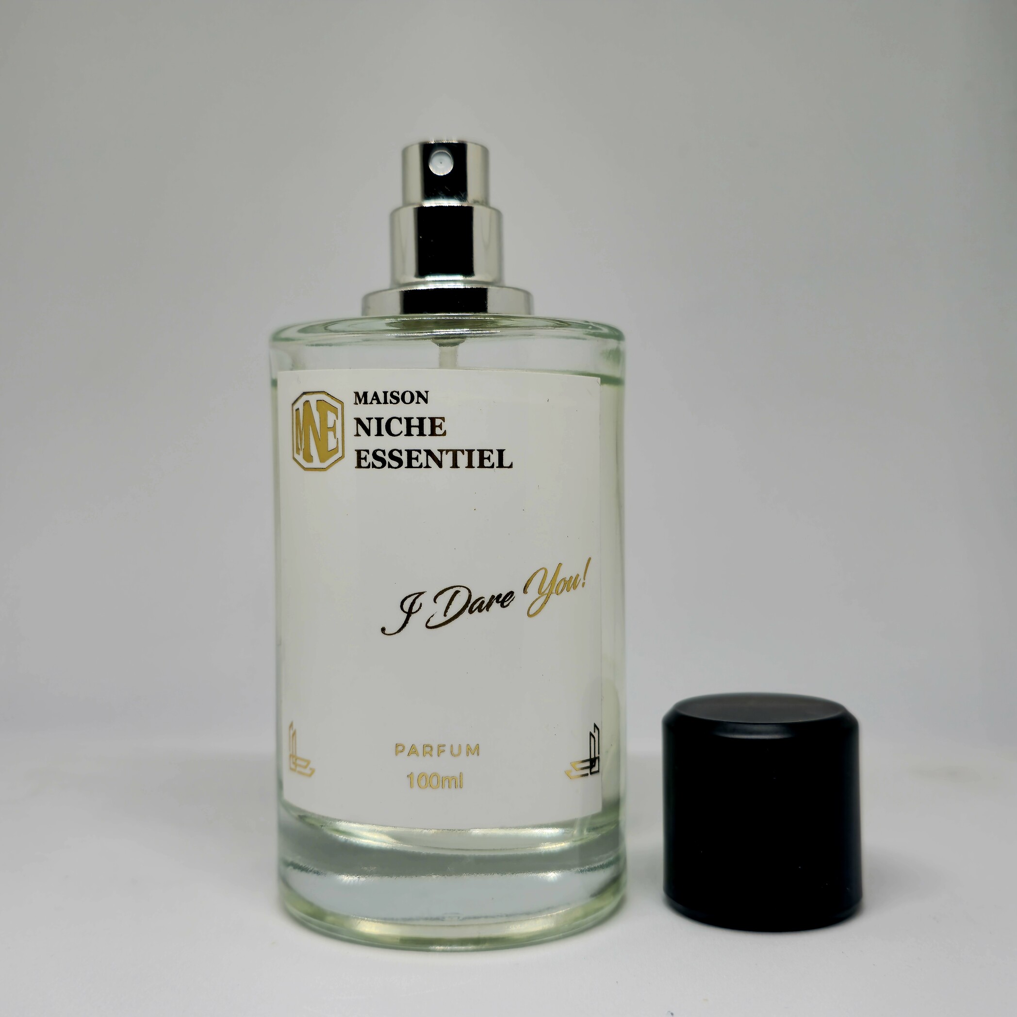 Clear glass perfume bottle labeled 'I Dare You!' with a black cap and silver spray nozzle.